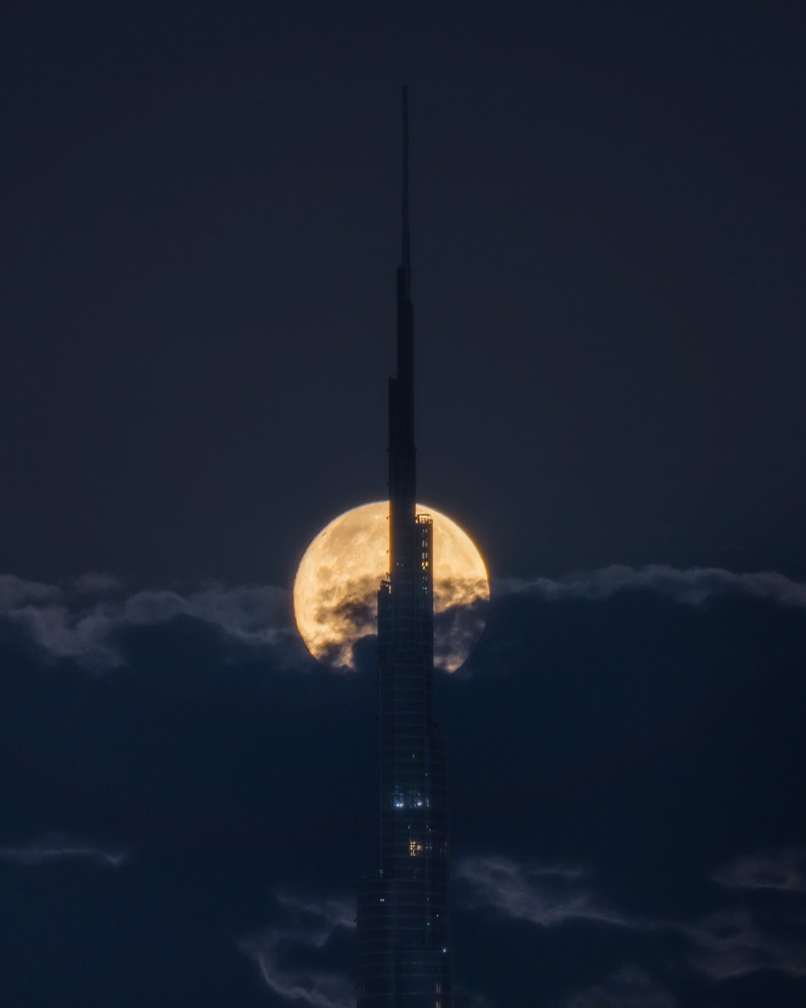 Alinhamento da superlua com o Burj Khalifa num céu dramático.