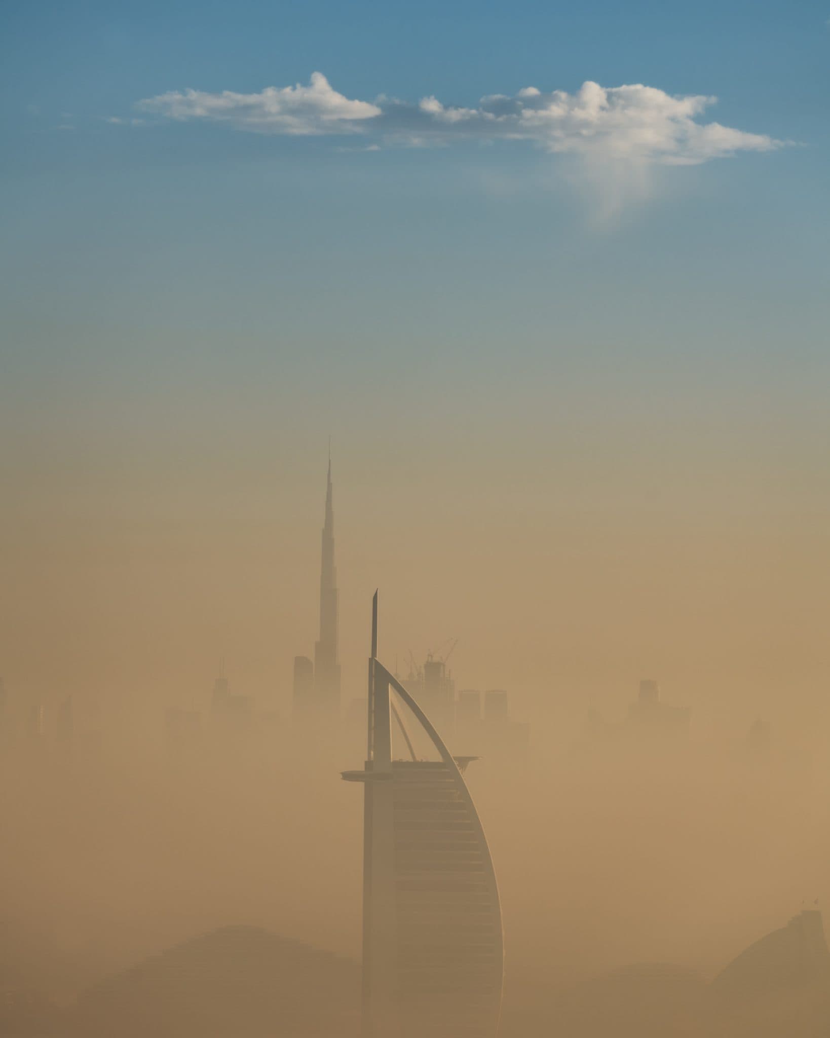 A neblina de Dubai ao nascer do sol, com o Burj Khalifa e o Burj Al Arab a erguerem-se acima da linha do horizonte