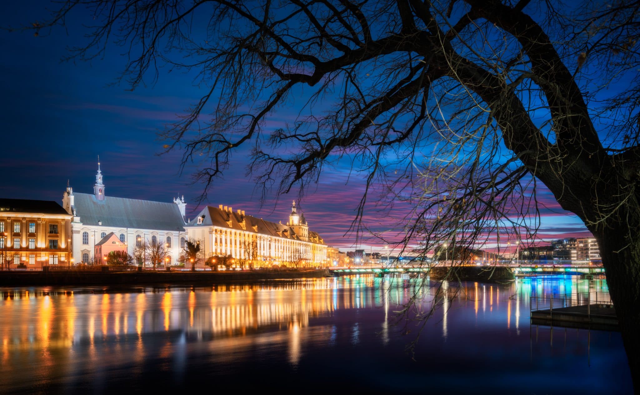 University of Wroclaw illuminated at dusk, reflected in the river as seen from Slodowa Island